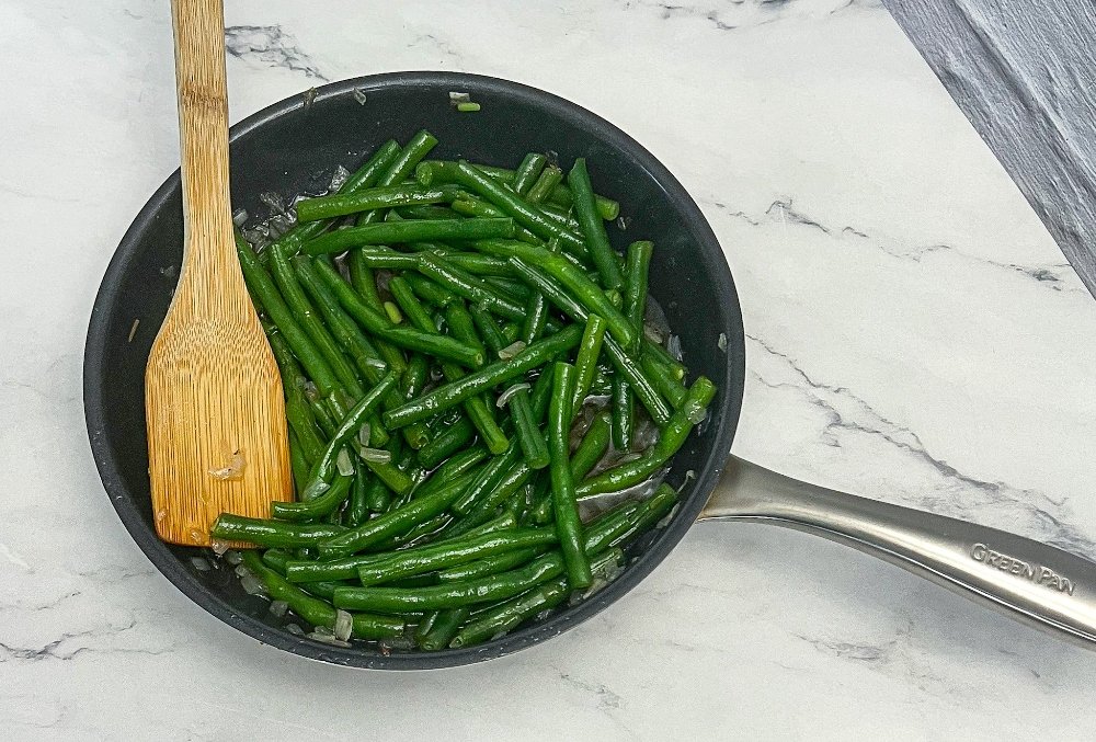 adding green beans to the pan