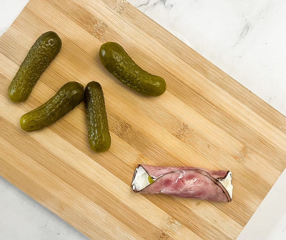 Rolling up the pickle in the ham and cream cheese