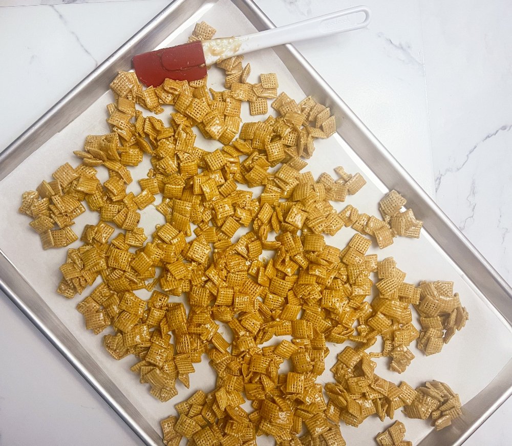 Spreading caramel chex crunch on baking sheet